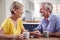 Retired Couple Sitting Around Table At Home Having Morning Coffee Together