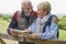 Retired Couple On Walking Holiday Resting On Gate With Map