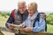 Retired Couple On Walking Holiday Resting On Gate With Map