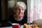 Retired elderly lone woman in the kitchen of his house sitting at the table