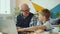 Retired grandfather and happy grandson using laptop talking laughing in house