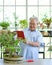 Retired grandfather use tablet computer to take a picture of a new bonsai tree. The morning atmosphere in the greenhouse planting