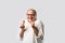 Retired Indian old man eating ice cream, standing icolated against white background