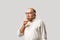 Retired Indian old man eating ice cream, standing icolated against white background