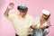 retired man gesturing while wearing virtual reality headset near wife on pink.