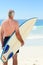 Retired man with his surfboard at the beach