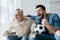 Retired man watching championship and cheering with handsome son holding football