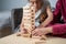 Retired mother and daughter spend time together at home, playing board game and caressing dachshund dog. Caucasian senior woman