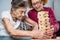 Retired mother and daughter spend time together at home, playing board game and caressing dachshund dog. Caucasian senior woman