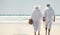 retired ouple white dressed walking on the beach