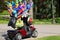 Retired riding a scooter with colorful balloons for sale in the park