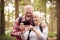 Retired Senior Couple Hiking In Woodland Countryside Taking Photo With Mobile Phone