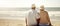 retired senior couple sitting and relaxing in sand on the beach. copy space
