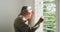 Retired senior man in cardigan sweater looking out through window blinds at home