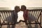 Retired senior multiracial couple sitting on folding chairs kissing each other at beach