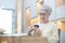 Retired woman holding coffee cup sitting at home alone homeless, lonely, sad, contemplative, alone. View through window glass