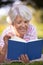 Retired woman reading book on park