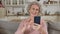Retired woman sends air kiss against smartphone front camera