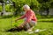 Retired woman watering little tree near cottage house