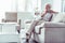 Retired woman wearing beige trousers and white blouse waiting for husband