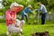 Retired woman wearing gloves feeling tired after working in garden