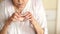 Retiree washes down a tablet with water from a glass. Pharmacy concept. Hands of an old woman on the background of