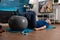 Retirement senior man doing wellness warming legs up using swiss ball sitting on yoga mat