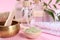 Retreat concept. Singing bowl, spirulina powder, towel and soap bars on pink background, closeup