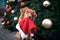 retriever dog holding santa hat in mouth in front of a christmas tree