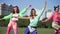 Retro aerobics workout of three joyful young fit sportswomen outdoors in sunlight. Portrait of happy positive confident