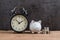 Retro alarm clock with white piggy bank and stack of coins on wooden table and black background as long term savining money or re