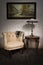 Retro armchair, table lamp on antique table and hanged painting
