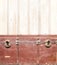 Retro background with red vintage chest upholstered in leather with brass snaps and wall with wooden boards. Product display