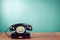 Retro black telephone on wooden table in front gradient mint blue background. Vintage style photo