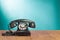 Retro black telephone on wooden table front gradient mint green background. Vintage style photo