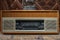 Retro broadcast radio receiver with blue eye light on wooden table circa 1950 front retro wall background. Listen music