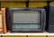 Retro broadcast radio receiver on wooden shelf against yellow background