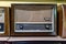 Retro broadcast radio receiver on wooden shelf against yellow background