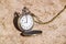 Retro bronze opened pocket watch on dry ground, 9 o`clock on the dial