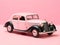 Retro car parked on pink background