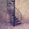 Retro cast iron spiral staircase on the background of an old wall and floor boards