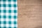 Retro checkered tablecloth on old oak textured wooden table background. Vintage style photo