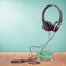 Retro compact cassette with rolls and headphones front mint blue background. Vintage style filtered conceptual photo