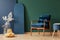 Retro dark blue armchair in elegant, living room interior with copy space on empty green and blue wall