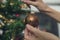 Retro image of female hands hanging shiny brown holiday bauble