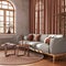 Retro living room with curtains, fabric sofa and rattan carpet in orange and beige tones. Parquet floor and arched window.