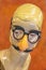Retro mannequin head with forehead curl wearing funny costume glasses with orange nose and mustache - isolated on orange