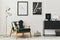 Retro and minimalist compositon of living room interior with design armchair, two mock up poster map, lamp, decoration, white wall
