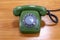 Retro mint green rotary telephone on wooden table.