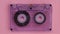 Retro music compact cassette reeling tape on pink background